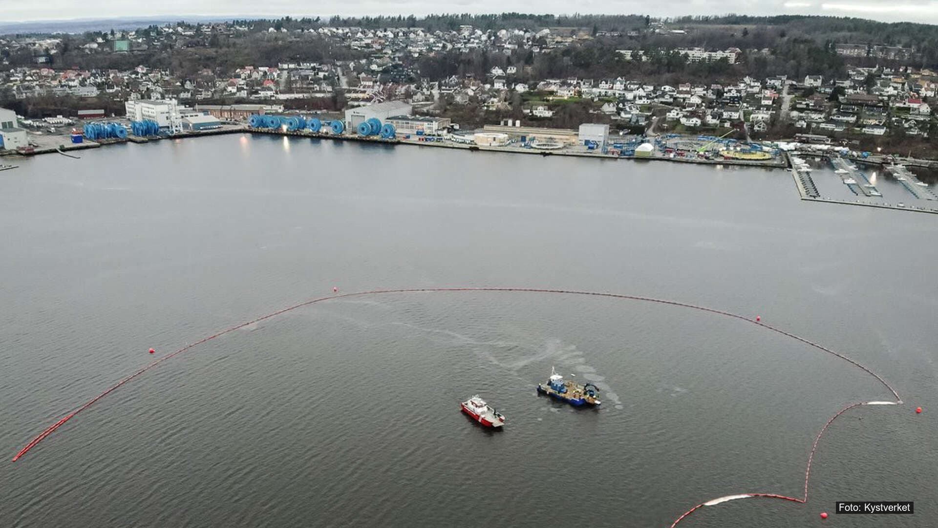 Flyfoto av Mossesundet der lenser og båter brukes for å samle opp forurensning i sjøen.